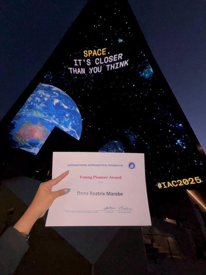 Young Pioneer Award certificate held up in front of an IAC 2025 sign
