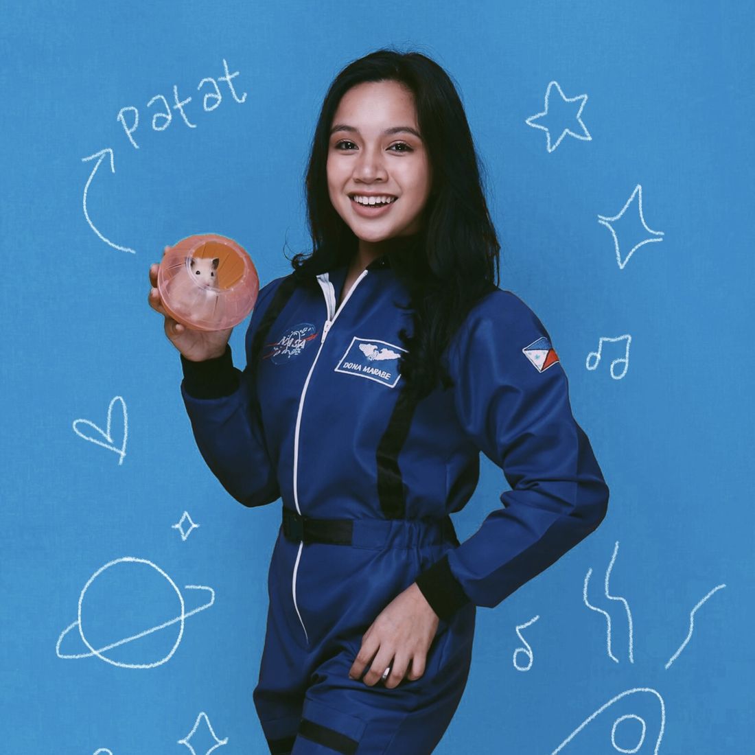 Dona in a blue flight suit against a doodled space backdrop